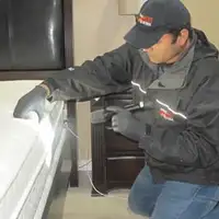 Bed bug inspection technician checking a mattress and bed frame for signs of infestation in Cincinnati, OH
