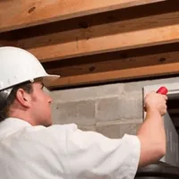 Termite inspection technician checking a basement wall and framing for termite activity in Cincinnati, OH