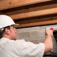 Termite inspection technician checking a basement wall and framing for termite activity in Cincinnati, OH